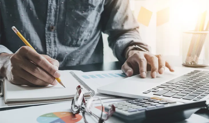 a man works with a notepad and computer while looking at graphical information