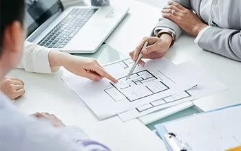 a group of professionals observe a floorplan pointing out key elements of the facility