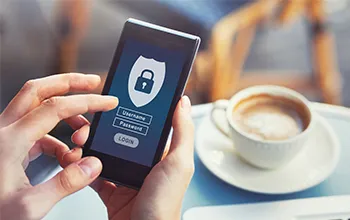 hands holding a phone showing a security validation process with a coffee in the background