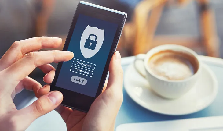 hands holding a phone showing a security validation process with a coffee in the background