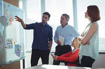 facilities managers gather around a whiteboard working to set goals