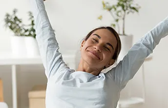 a young woman stretches up with a satisfied look, sitting in bright facilities fostering wellbeing