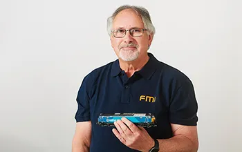 tim ireland, senior facilities management consultant, smiles at the camera, holding a model train