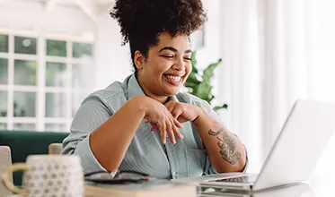 A young female facilities manager smiles at her computer in a brightly lit office