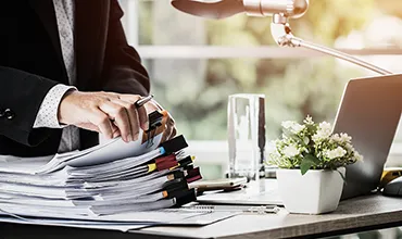 A faciliites manager searches through stacks of paper for the information he is looking for.