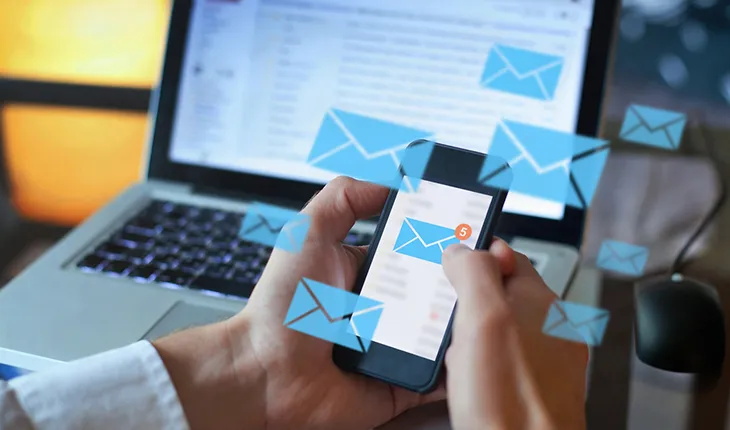 a facilities manager receives many work requests at one time via email, the a phone shows the mail icon with a red circle over it and the mail icon is repeated in a halo around the phone