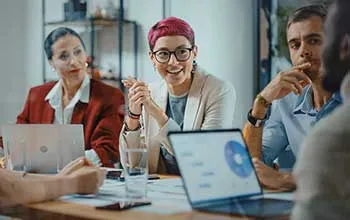 A group of facilities managers discuss findings in a graphical chart shown on a laptop, featuring a pie chart. 