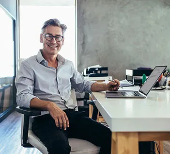 A facilities manager smiles up from a laptop 