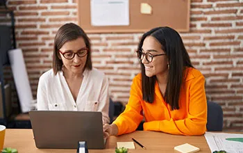 A facilities manager shows a facility user something on the screen, both are smiling indicating a high level of understanding. 