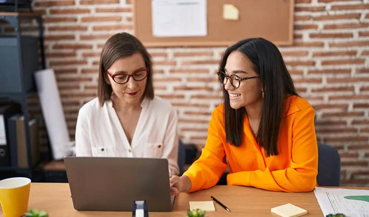 A facilities manager shows a facility user something on the screen, both are smiling indicating a high level of understanding.