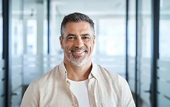 A mature male facilities manager smiles at the camera
