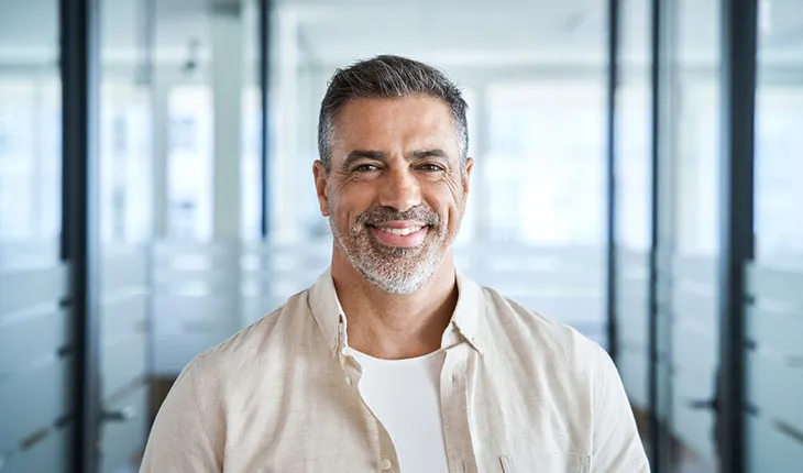 A mature male facilities manager smiles at the camera