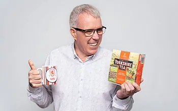Headshot of Ian Jackson, holding a football club mug and a box of yorkshire tea