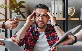 A facilities manager appears overwhelmed as multtiple hands holding phones, contracts and papers compete for attention