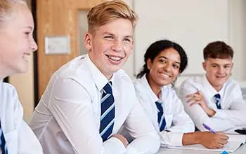 Private school students in formal uniform smile while sitting in class 