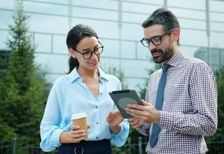 image of two facility managers in conversation, using a tablet device