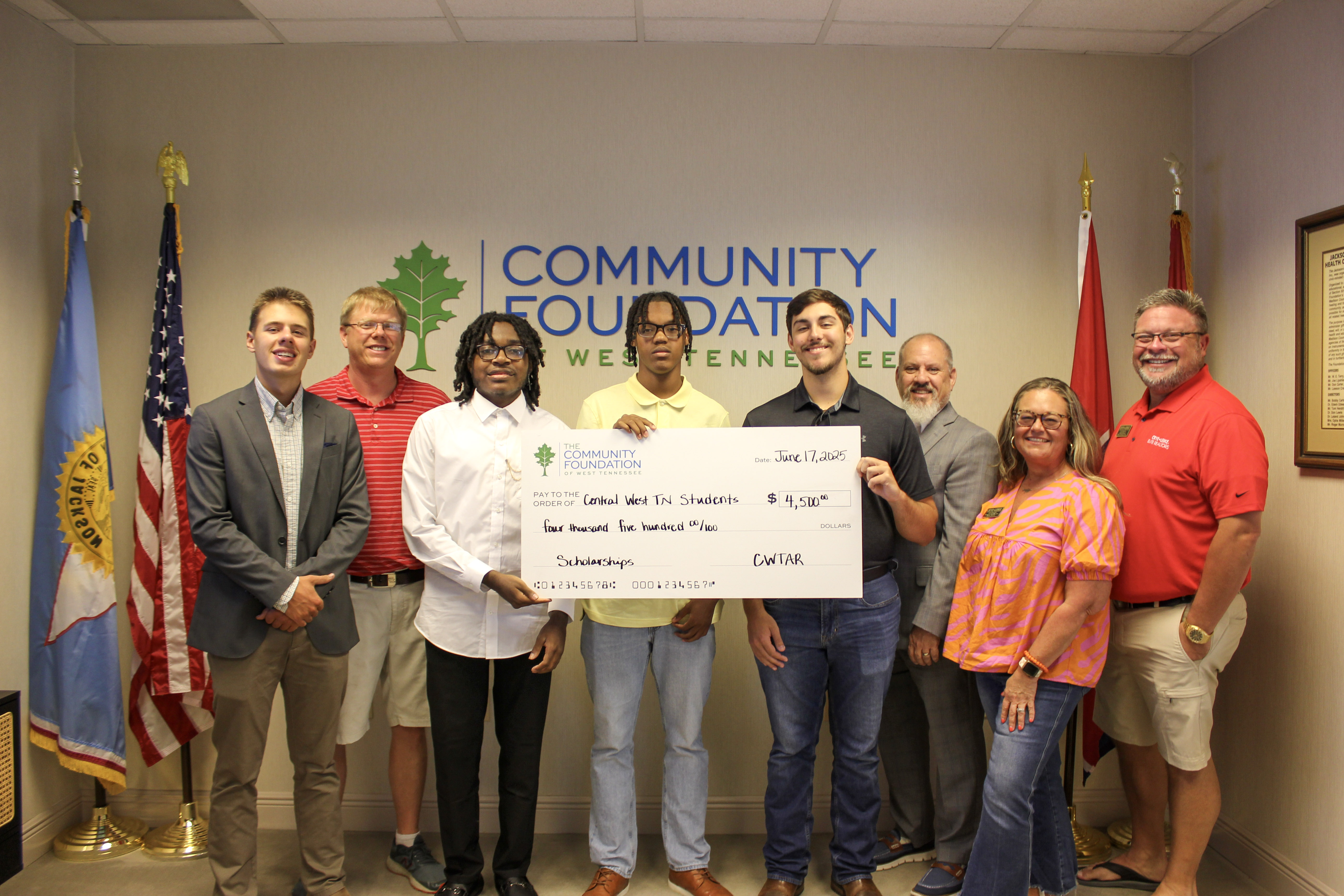 Scholarship recipients posing with a big check for $4,500