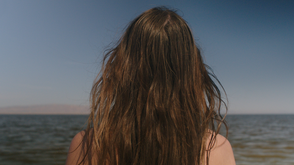 A person with their back to camera looks out over the sea.