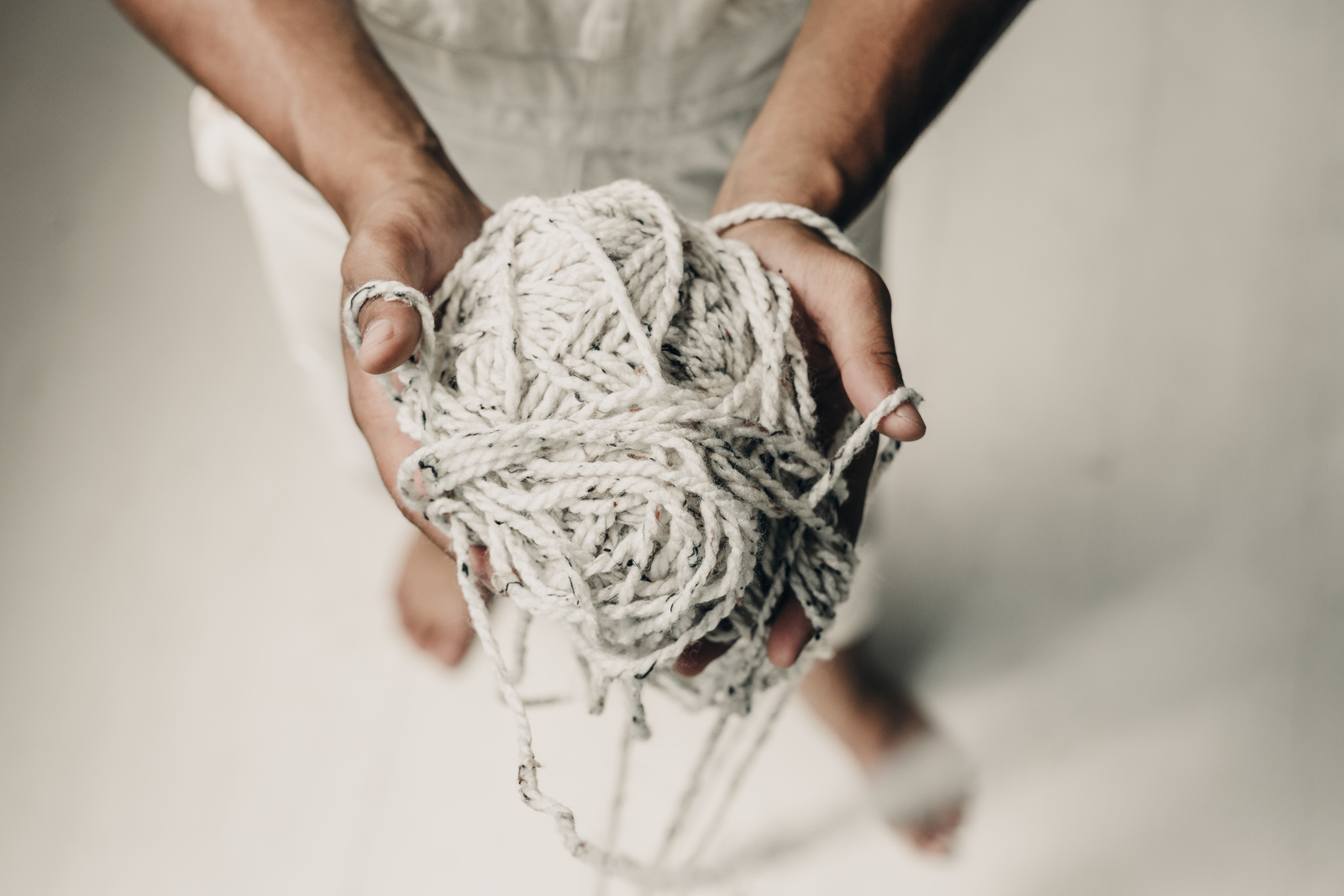 A close-up of hands holding a tangled ball of yarn.