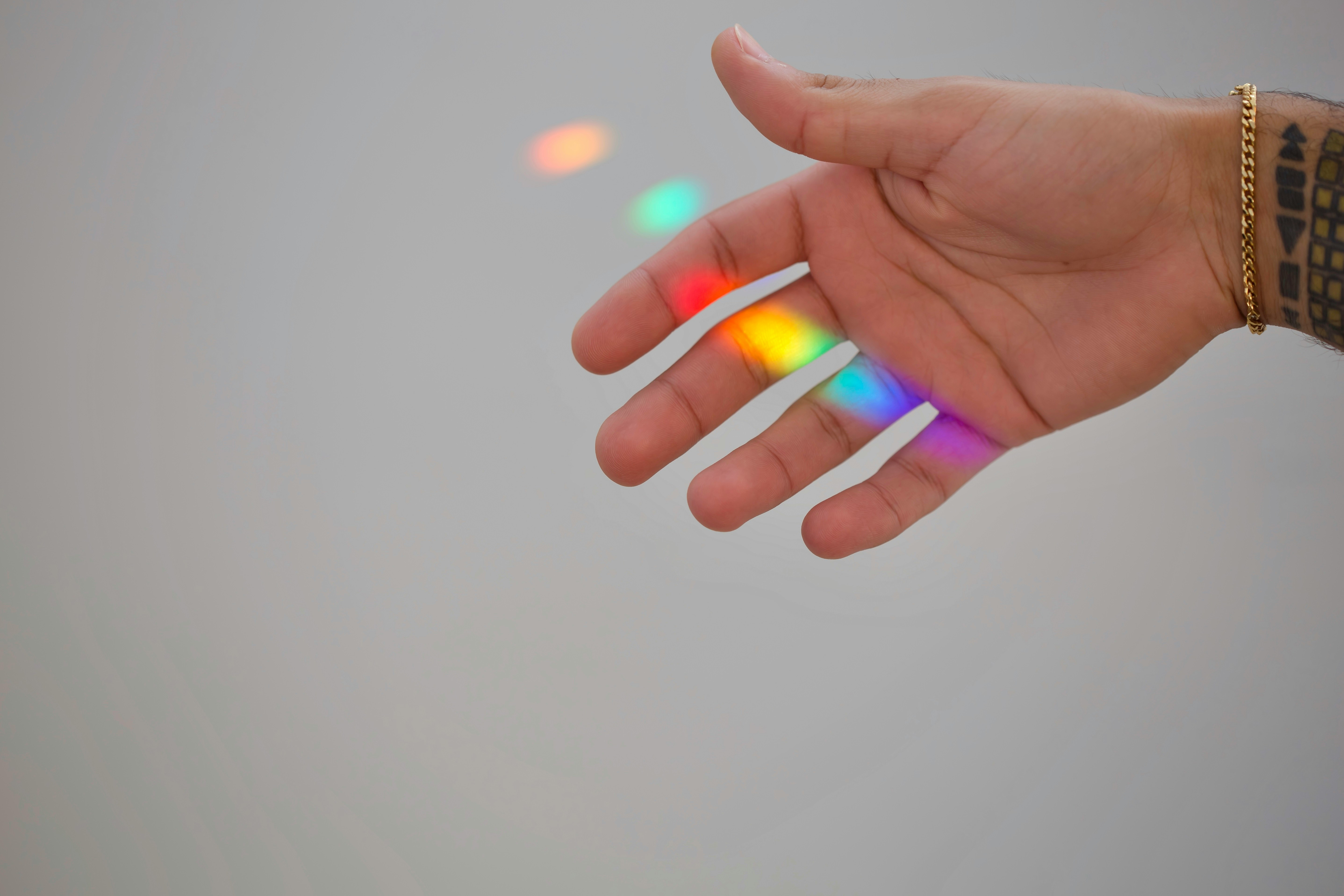 A hand stretched out under rainbow light.