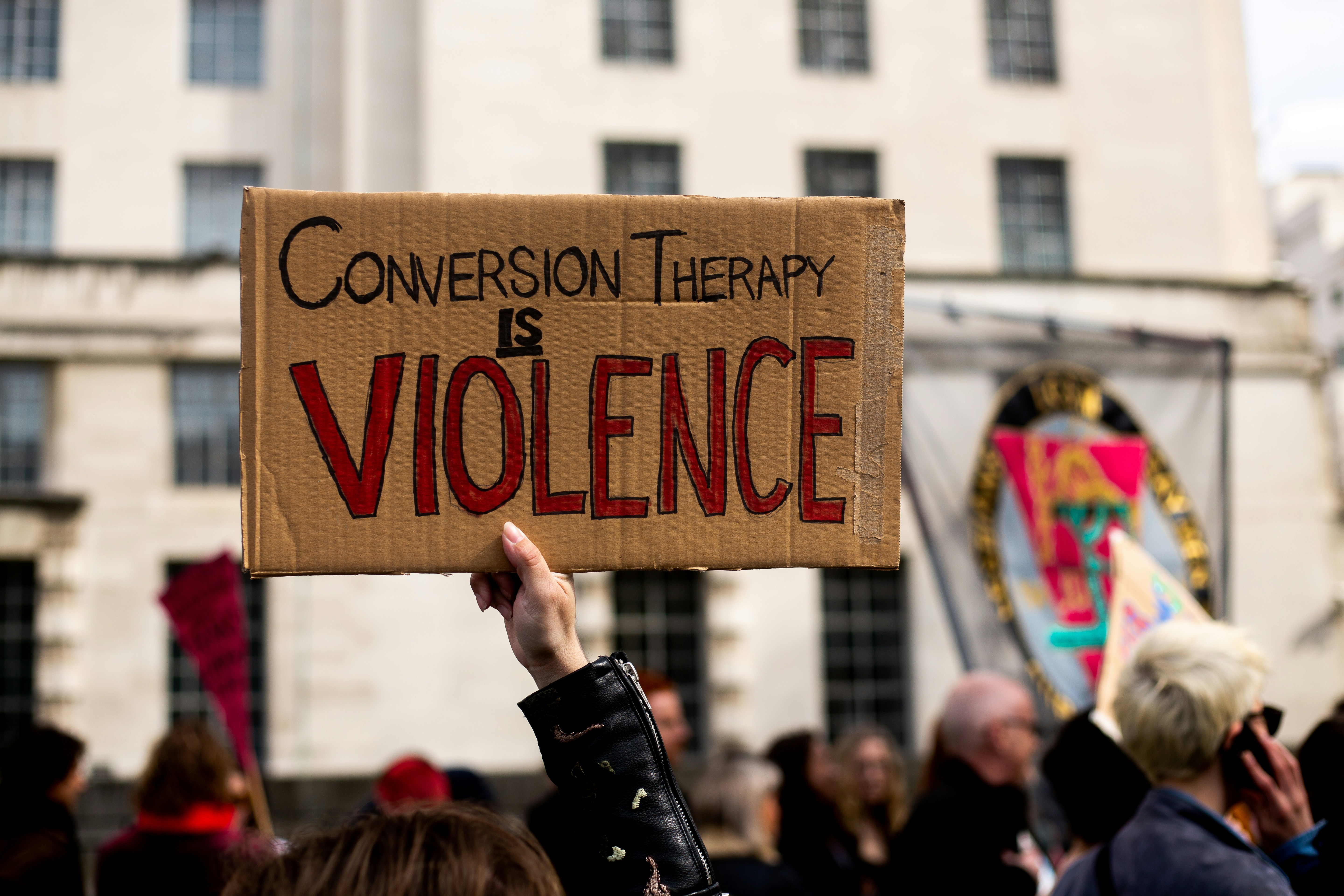 A protest sign reads: "Conversion therapy is violence".