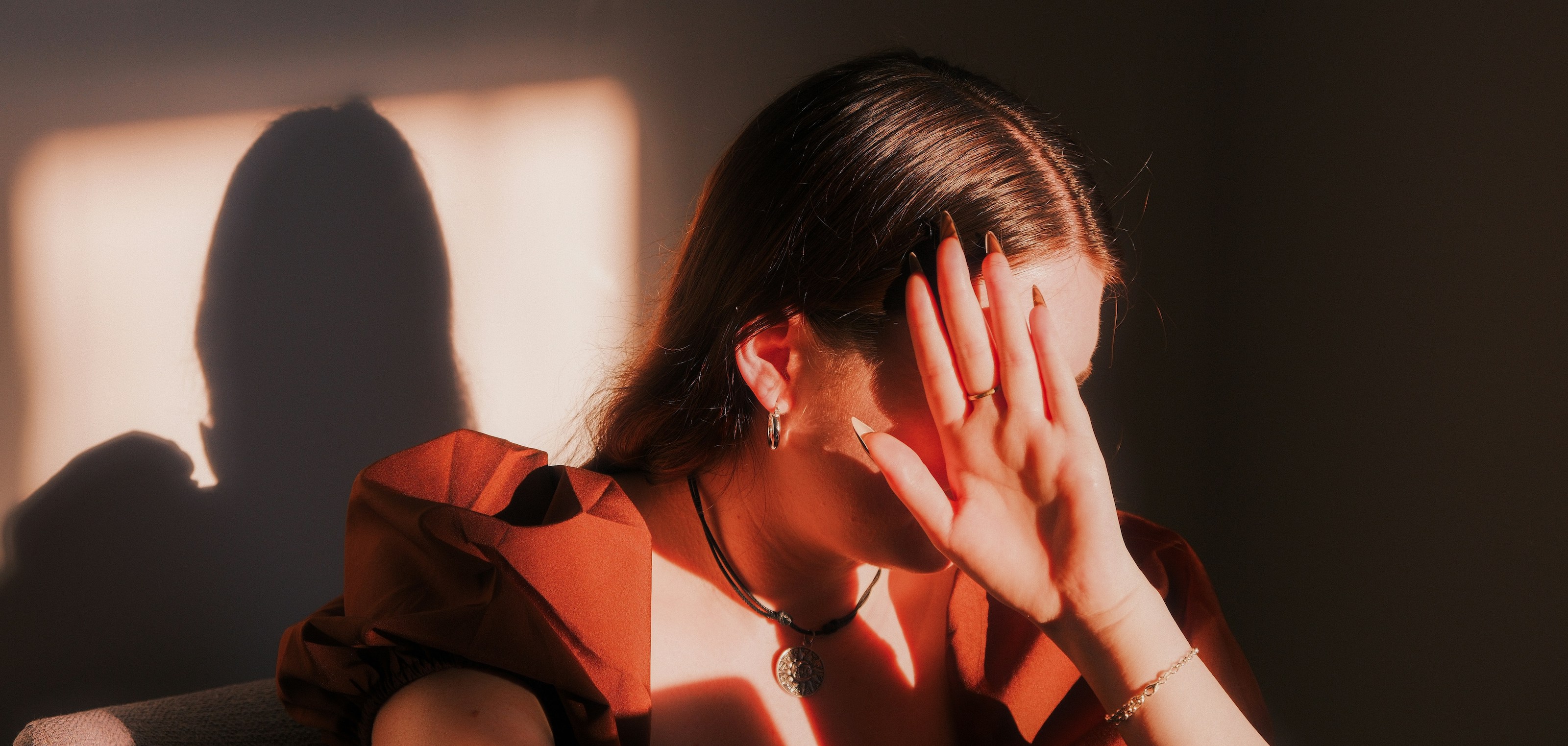 A white woman holds up her hand to shield her face from bright light.