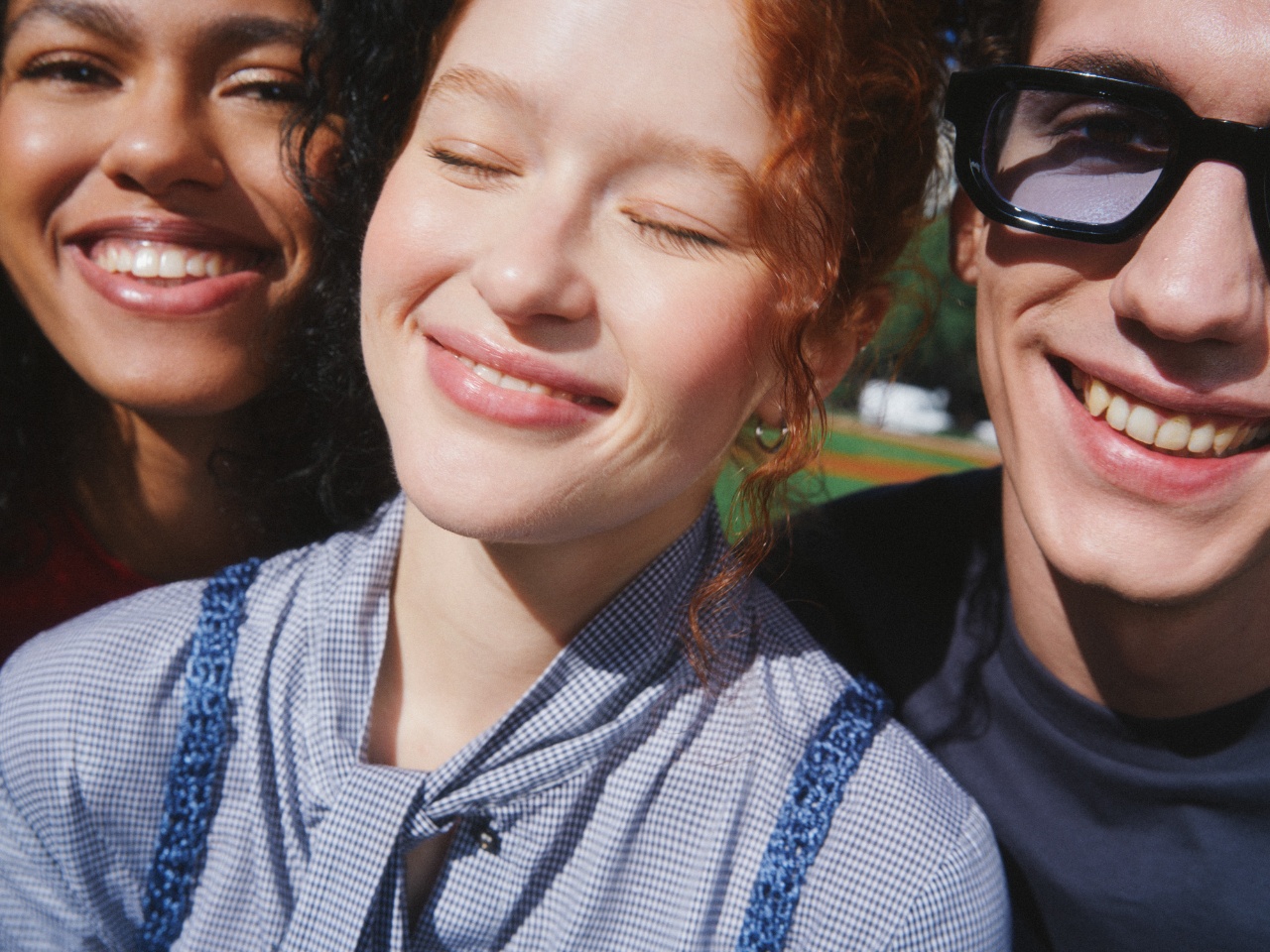 Close-up of three people smiling in the sun.