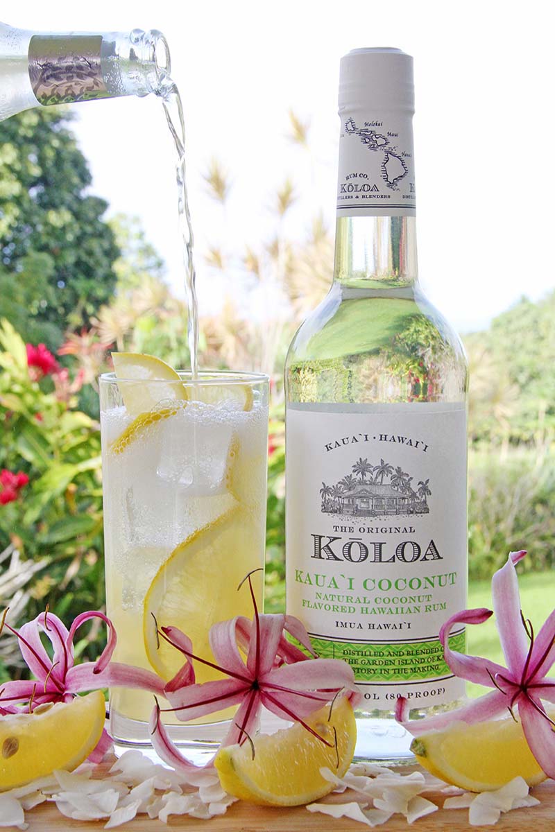 Pouring ginger beer into a part-full glass of coconut rum lemonade.