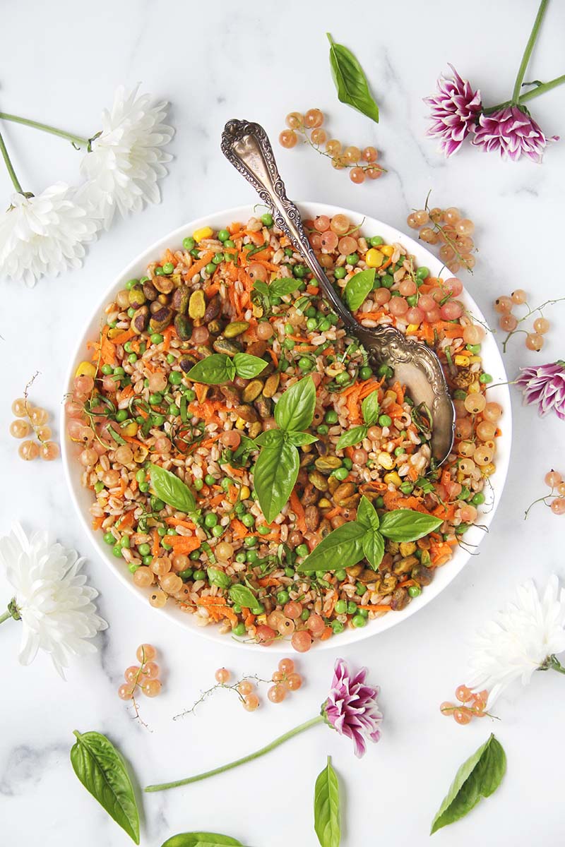 Bowl of vegetable farro salad, shown with a vintage serving spoon in the right side.