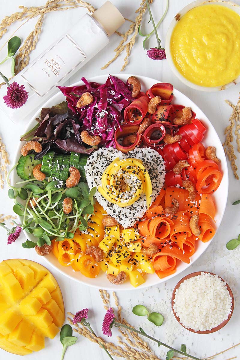Colorful vegan rice bowl meal with assorted raw vegetables in rainbow colors.