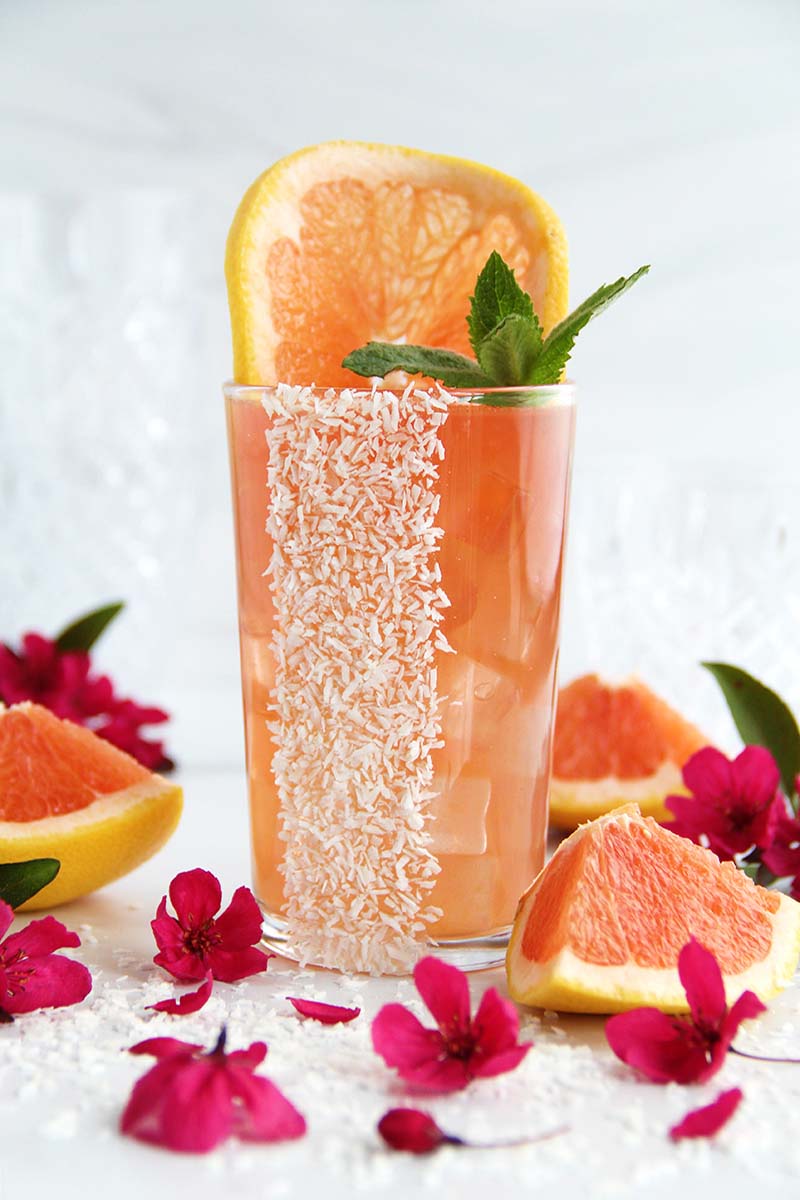 Coconut Paloma cocktail made with coconut rum, tequila, and grapefruit juice, garnished with grapefruit and fresh mint.