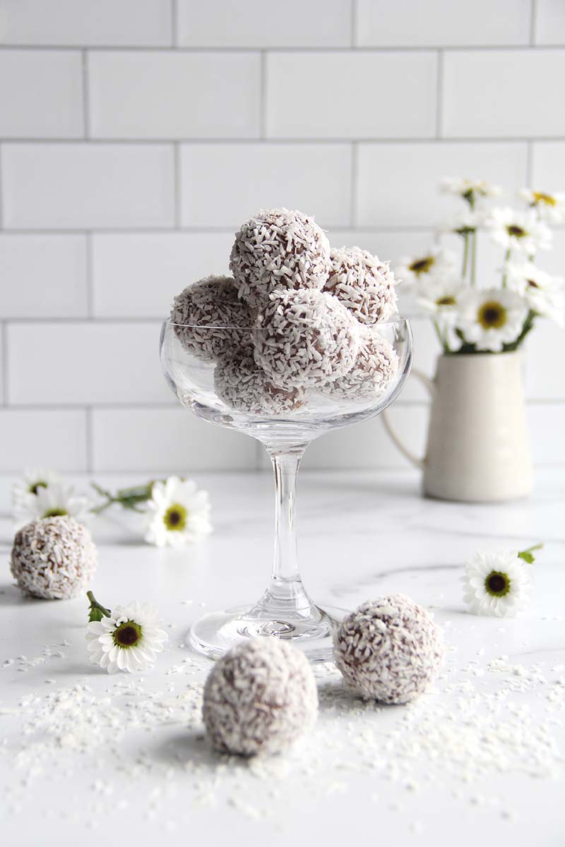 Several chickpea truffles in a serving dish, shown in a white kitchen with white flowers.