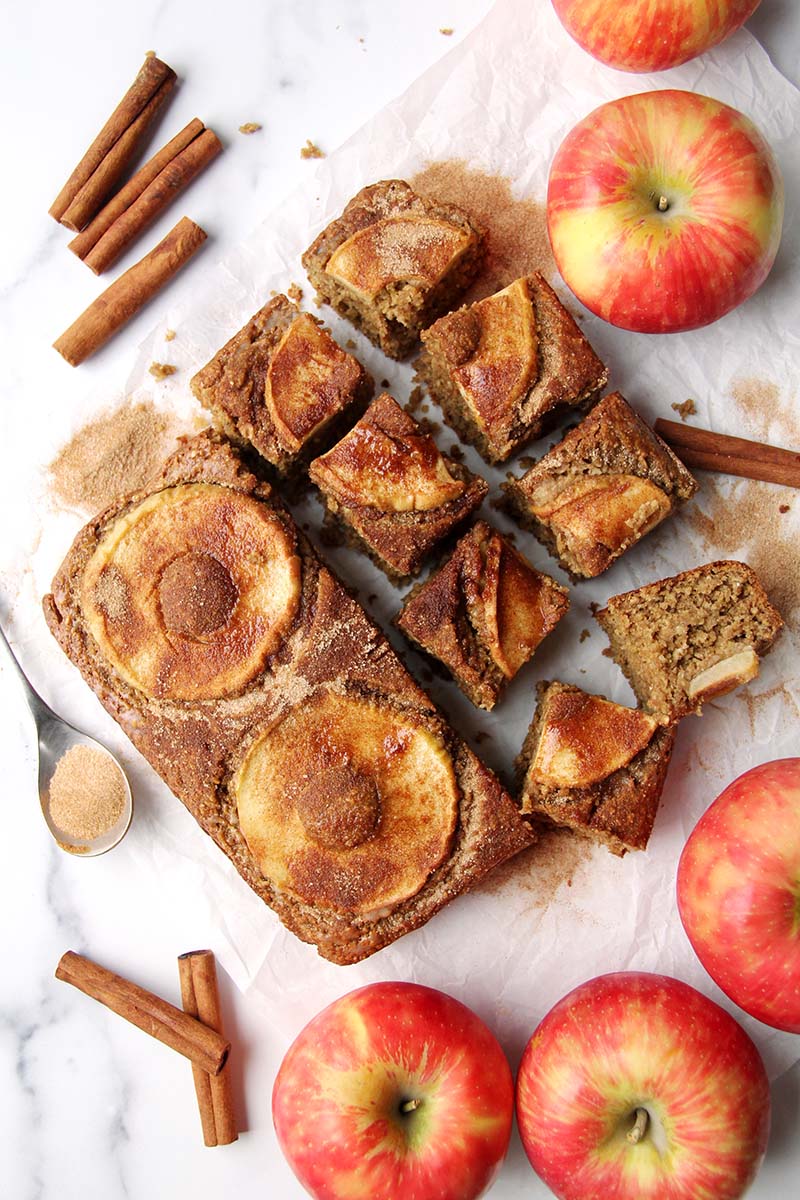 Apple cider donut cake partially cut, with some large slices and some smaller slices.