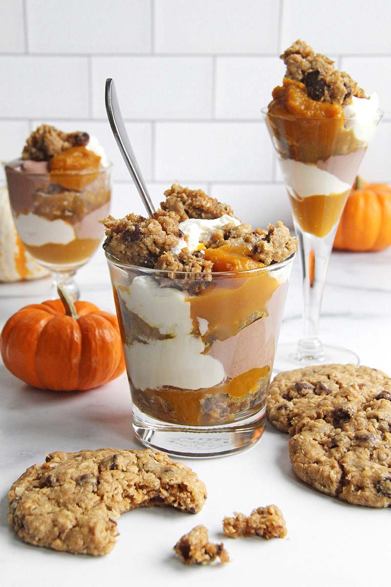 Three pumpkin cookie trifles, all in different serving glasses; the trifle in the front as a spoon in it.
