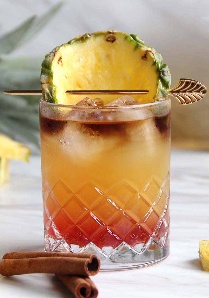 Close-up of a Chai Tai cocktail, showing the three colorful layers.