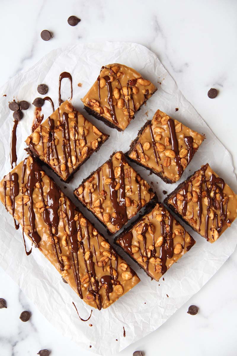 Vegan and grain-free Snickers brownies cut into squares, showing the texture of the creamy peanut butter caramel topping.