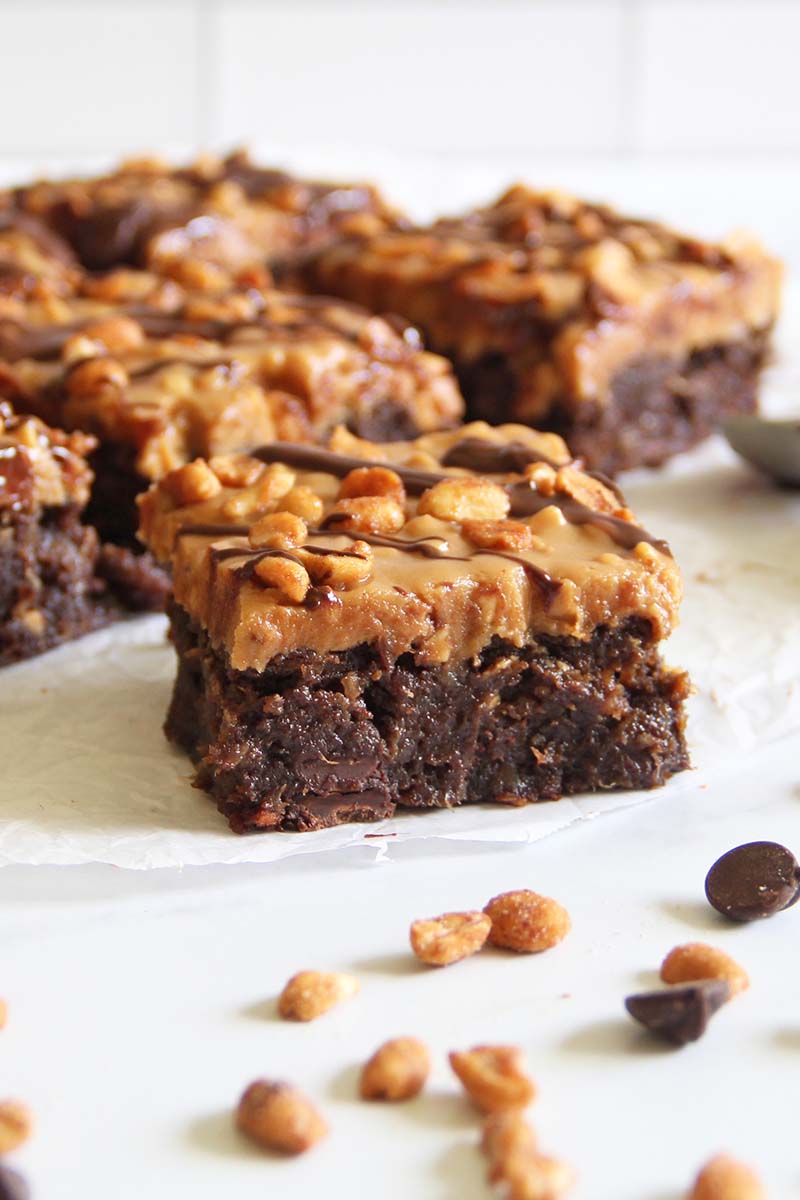 Side view of a vegan Snickers brownie showing the rich, fudgytexture of the date brownie base.