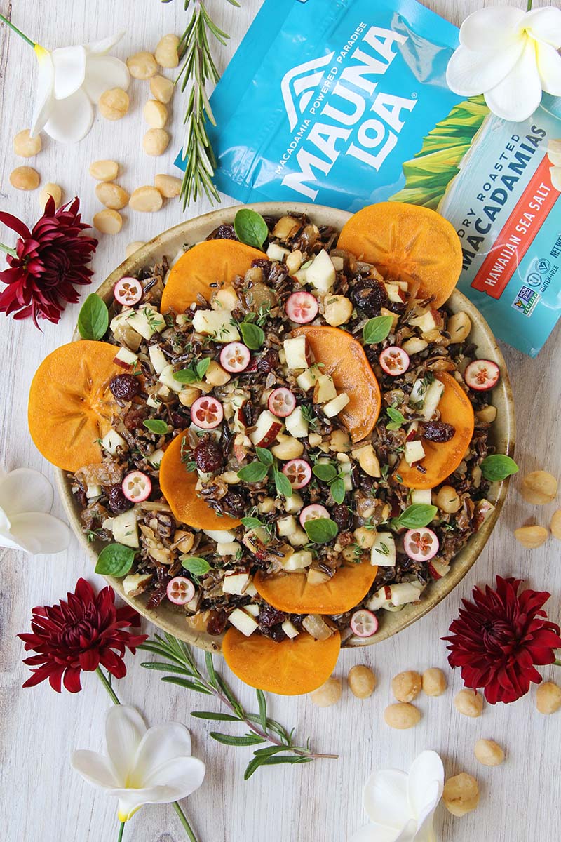 Healthy vegan wild rice stuffing shown with a bag of macadamia nuts and sprigs of rosemary.