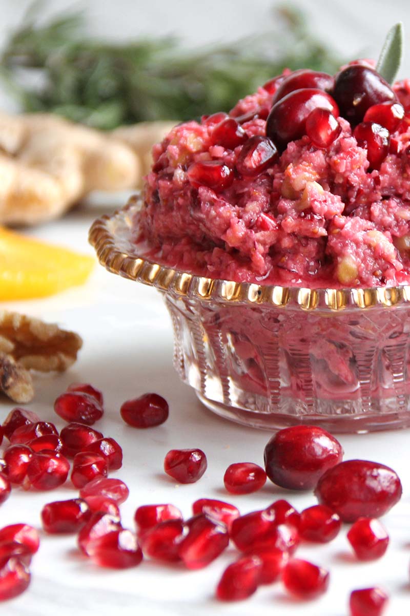 Close-up of an antique glass serving bowl heaped with no-cook pomegranate cranberry sauce.
