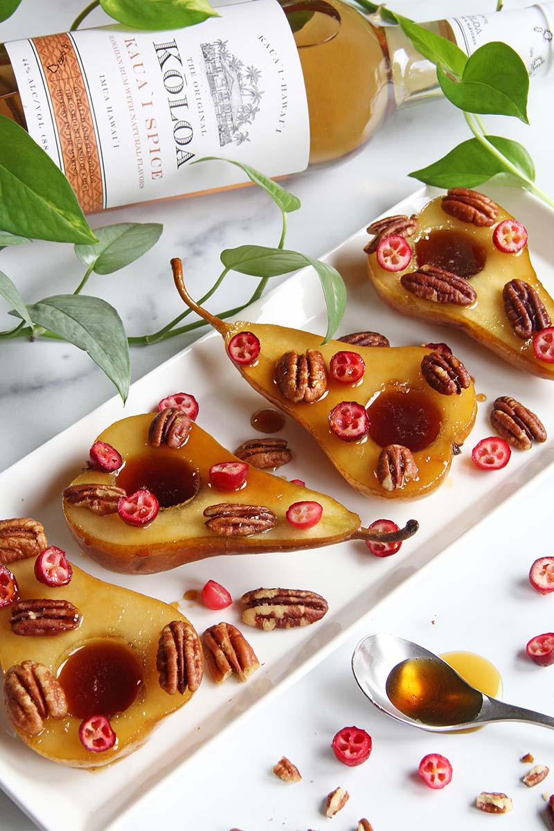 Vegan rum poached pears, shown next to a bottle of spiced rum.