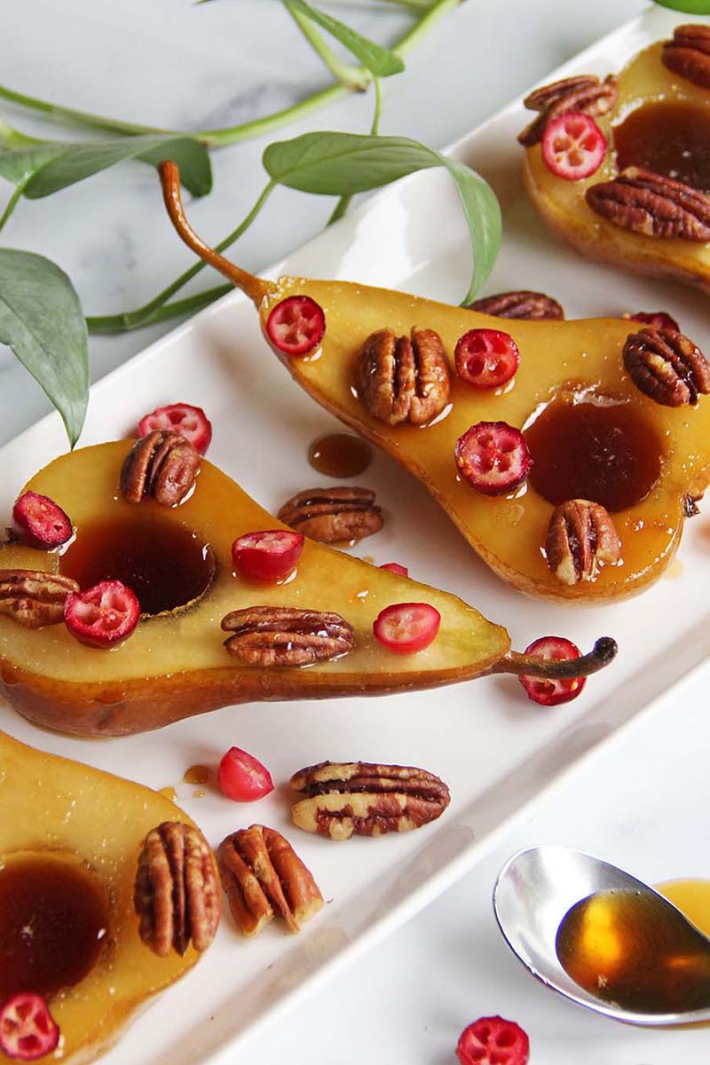 Close-up of rum poached pears garnished with fresh cranberries and toasted pecans.