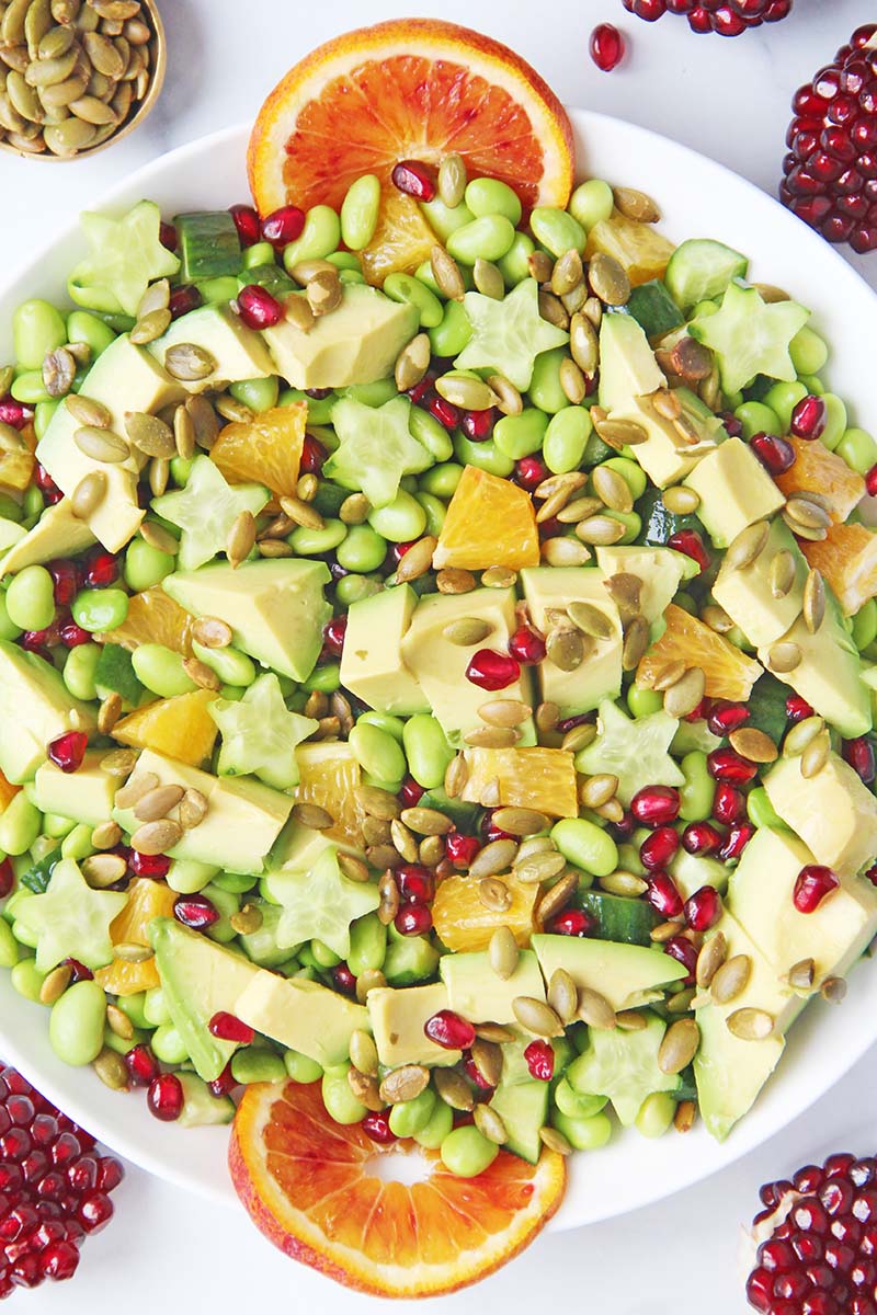 Close-up of a winter edamame salad with orange, pomegranate, cucumbers, avocado, and pepitas.
