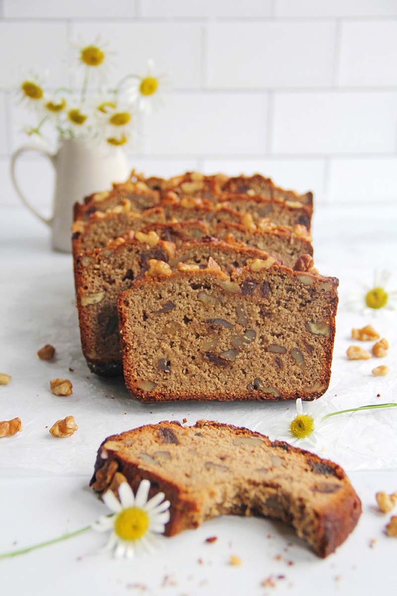 Freshly sliced chickpea flour banana bread in a white kitchen setting, with one slice on its side highlighting the fluffy but hearty texture.