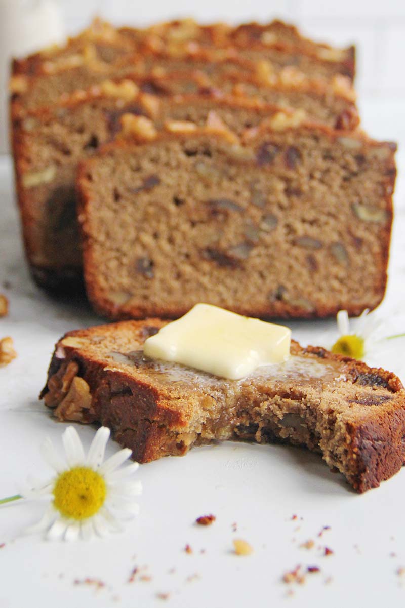 Close-up of a cut loaf of chickpea flour banana bread with slices arranged in a staggered pattern, including one slice turned on its side in the foreground to show the moist, hearty texture.