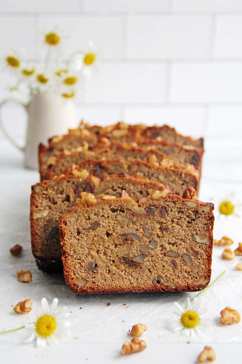 Sliced chickpea flour banana bread in a white kitchen setting, showing slices and a deep golden brown crust.