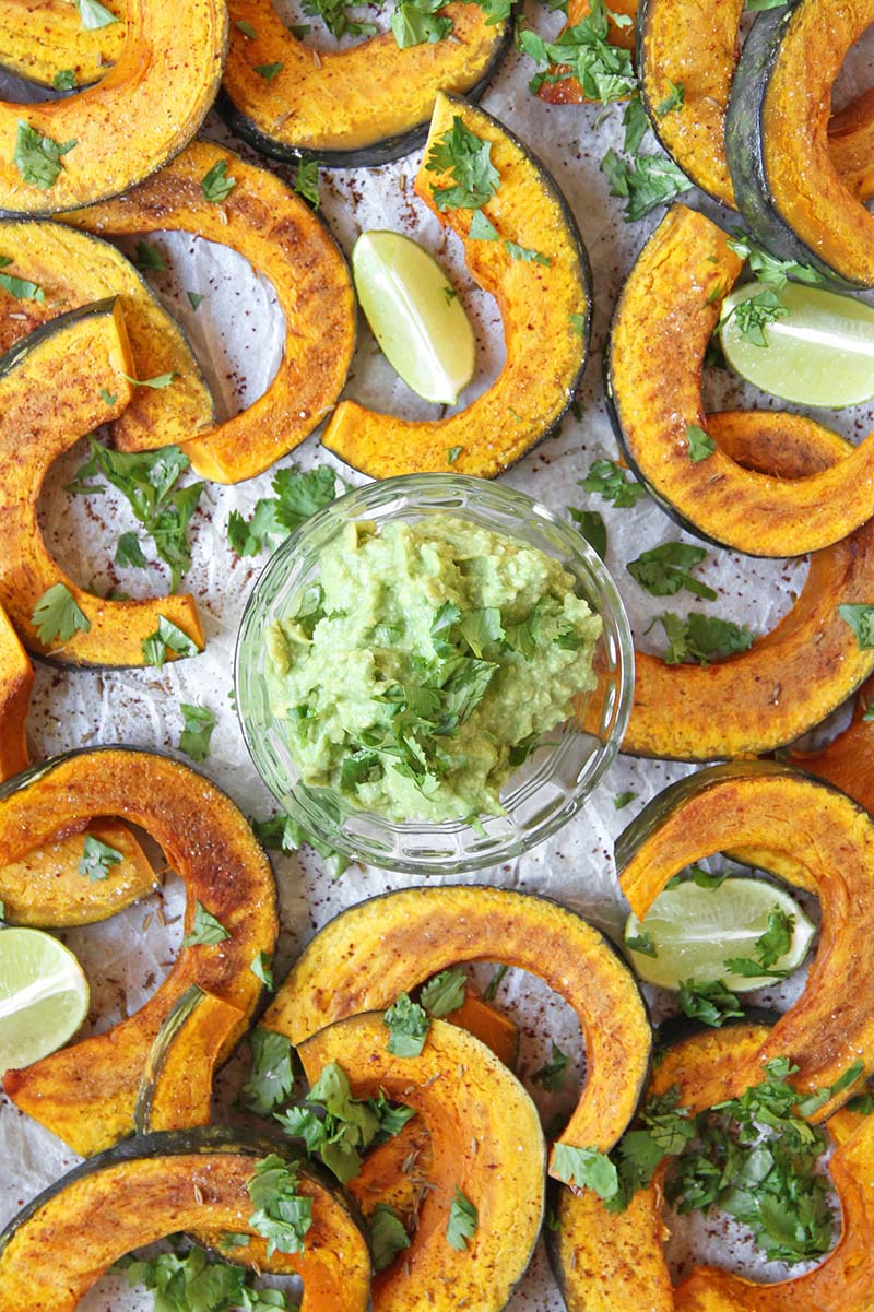 Close-up of healthy chili- and cumin-roasted kabocha squash dippers with cilantro and lime, paired with guacamole for dipping.