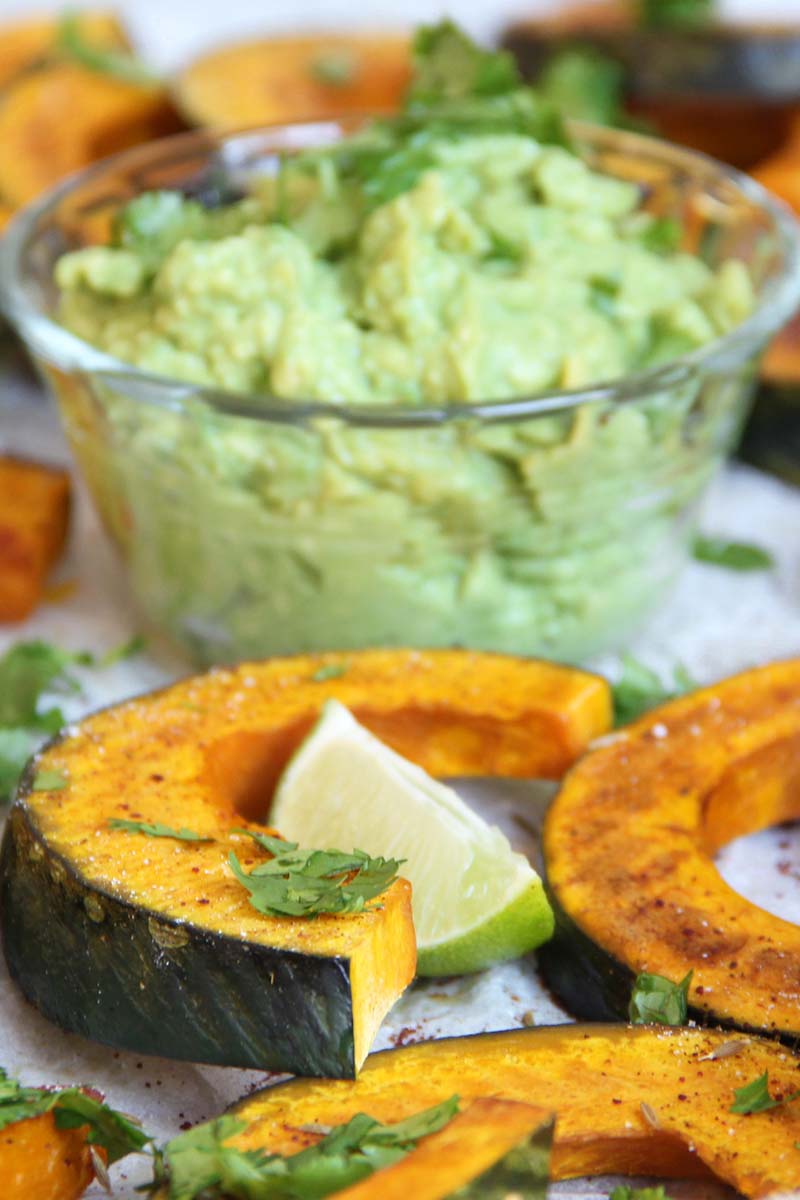 Side view of a platter of Mexican-inspired kabocha squash dippers roasted with chili and cumin, finished with cilantro and lime, and served with guacamole for dipping.