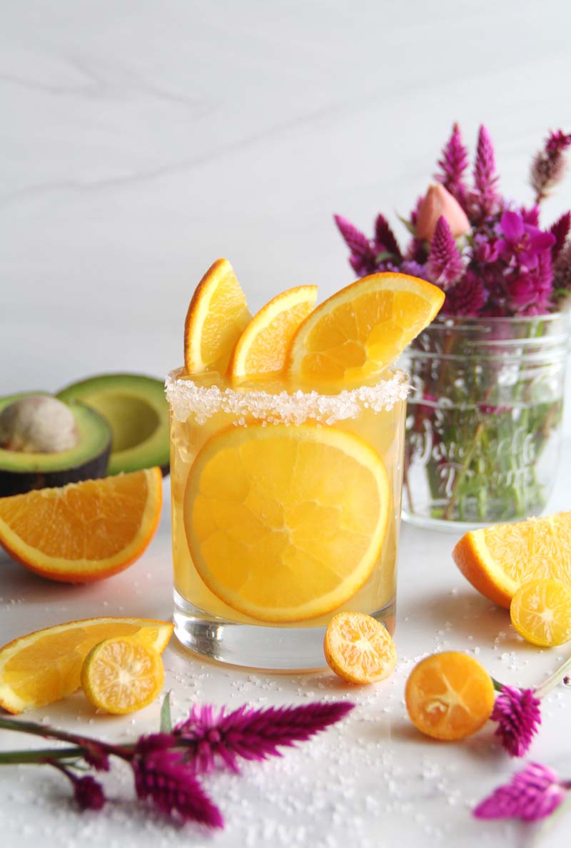 Orange margarita made with tequila and spiced rum, finished with a salted rim and fresh citrus slices, for cozy winter entertaining.