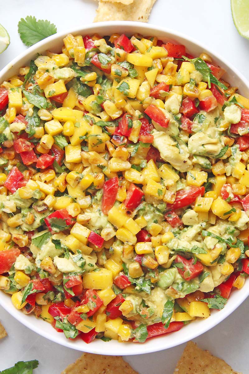 Close-up of a serving bowl of corn and mango salsa with avocado, jalapeños, and cilantro.