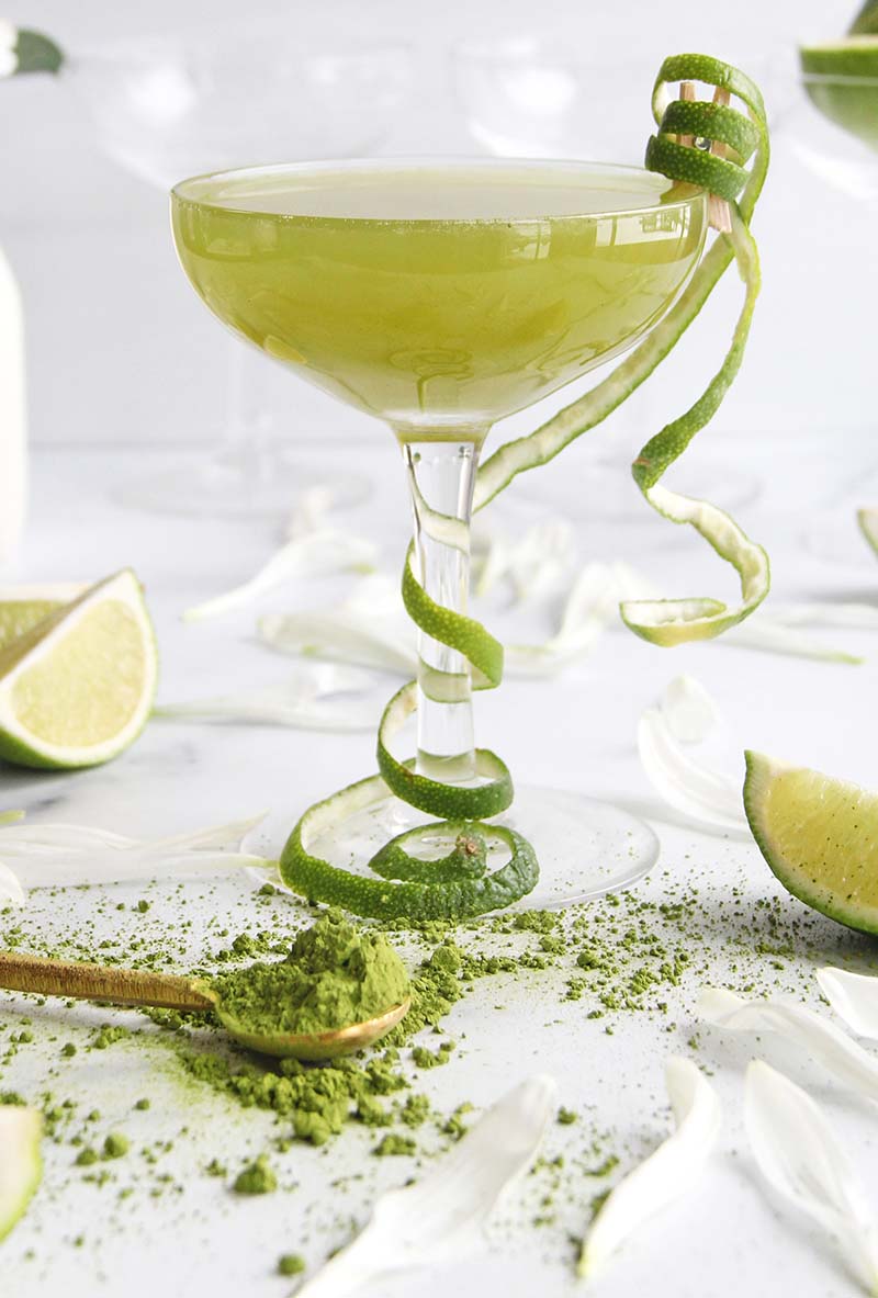 Close-up of a Matcha Coconut Daiquiri with bright green color, presented with a lime peel garnish in a coupe glass.